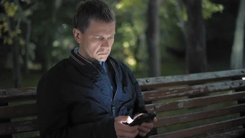 Sad Man Writes a Message to His Unsupported Girl on a Date Sitting at Night in Stock Footage 97740912