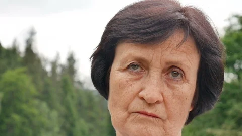 Sad mature lady with short dark hair and wrinkles on her face is looking at the Stock Footage