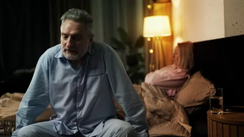 Sad middle-aged man and wife sitting apart on bed, facing relationship issues Stock Footage 321615839