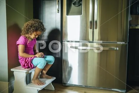 Sad Mixed Race Girl Sitting Near Refrigerator