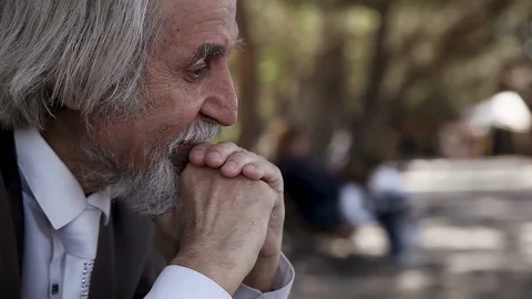 Sad old crazy man in a suit thinks, mutters, prays in the park Stock Footage 96480361