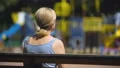 Sad old female sitting on playground bench and looking at children, infertility HD Footage