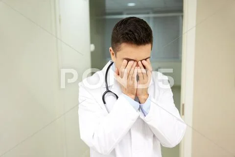 Sad or crying male doctor at hospital ward Stock Photos
