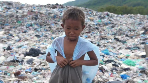 Sad Poor Boy Walking On Garbage Dump 스톡 동영상 153713525