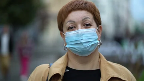 Sad red-haired middle-aged woman in wears a medical mask on the street to preven Stock Footage 212024845