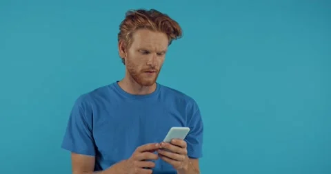 Sad redhead man throwing smartphone isolated on blue Stock Footage 136181003