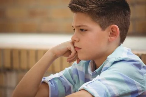 Sad schoolboy sitting alone on steps in campus Foto stock