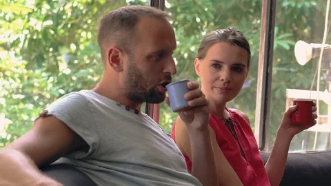 Sad, serious couple talking and drinking beverages sitting at home Stock Footage 73145527