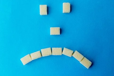Sad sugar face on the blue table. Sweet food is bad for your teeth. Stock Photos