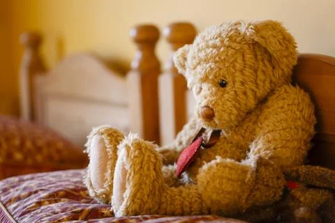 Sad teddy bear on a bed Stock Photos