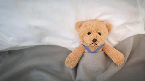 A sad teddy bear lies sick in bed with disappointment and discouragement Foto stock
