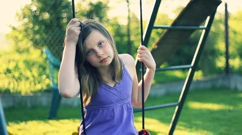 Sad teen girl sitting on the swing in the garden HD Stock Footage