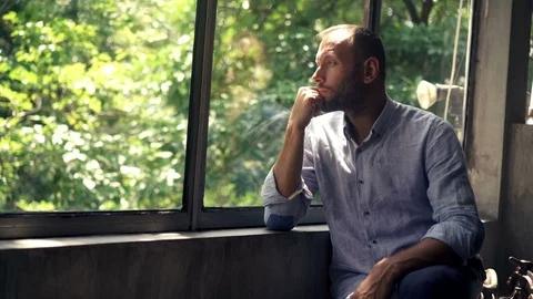 Sad, unhappy man looking by window at home, 4K Stock Footage 73153270