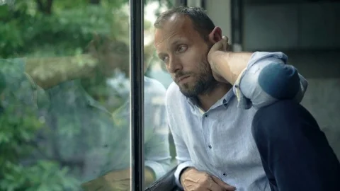 Sad, unhappy man looking by window at home, 4K Stock Footage 73154014
