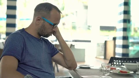 Sad, unhappy man sitting by table in cafe Stock Footage 80733316