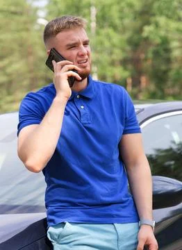 Sad upset guy driver is standing near broken car after road accident, crash Stock Photos
