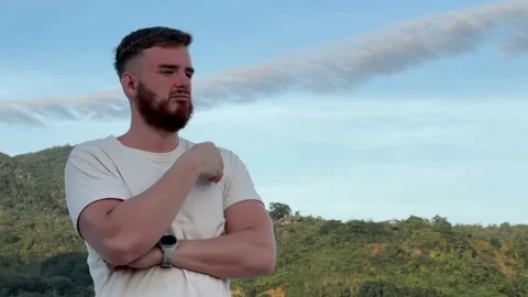 Sad upset serious bearded man standing outdoors in mountain at summer sunny day Stock Footage 232499384
