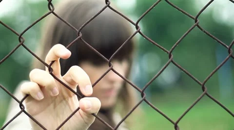 Sad woman behind chain-link fence, outdoors HD Stock Footage