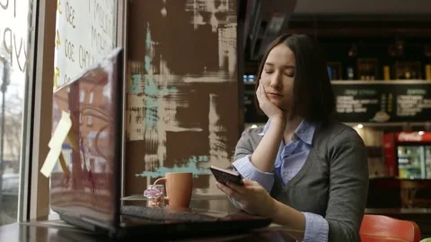 Sad woman in cozy cafe using smartfone Stock Footage 82625130