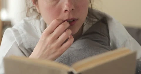 Sad woman crying while reading a book at home Stock Footage 131617614