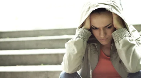 Sad woman in the hood sitting on the stairs, steadicam shot HD Stock Footage