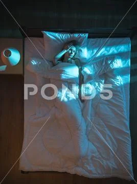 The sad woman lay on the bed. Evening night time. View from above Stock Photos