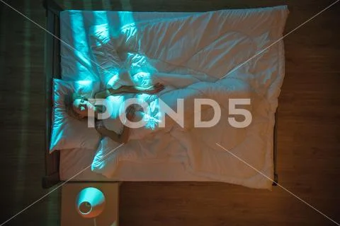 The sad woman lay on the bed. Evening night time. View from above Stock Photos