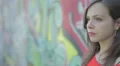 sad woman with a red shirt is crying leaning against a wall painted with murals HD Footage