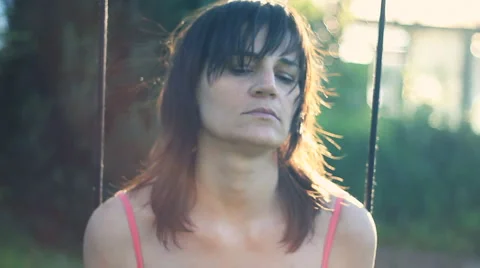 Sad woman sitting on the swing in the garden, dolly shot HD Stock Footage
