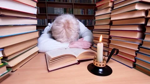 Sad woman using candle reading book in library. Stock Footage 220171495