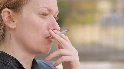 Sad woman without makeup nervously smokes in the street Stock Footage 73579463