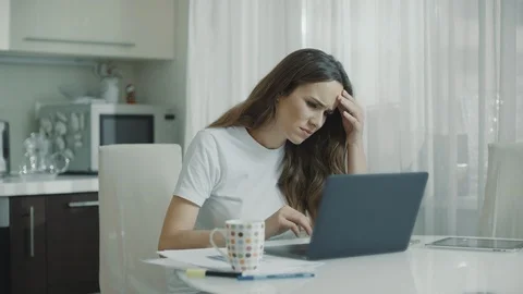 Sad woman working laptop at white kitchen. Unhappy person use computer Stock Footage 107763776
