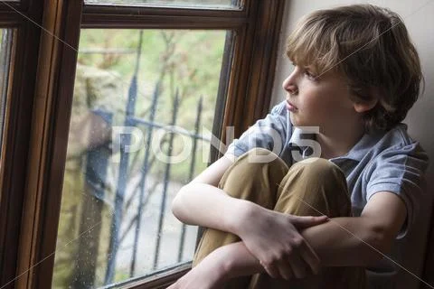 Sad young boy child looking out window Stock Photos