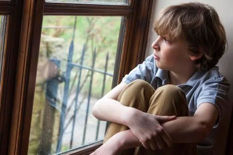 Sad young boy child looking out window Stock Photos