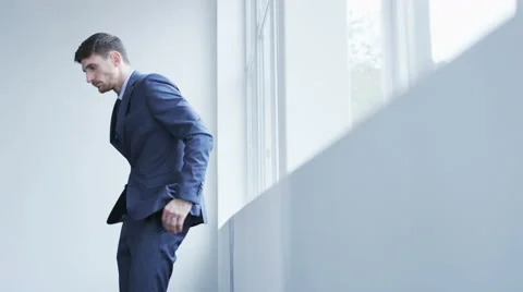 Sad young businessman standing back to a window Stock Footage 68404429