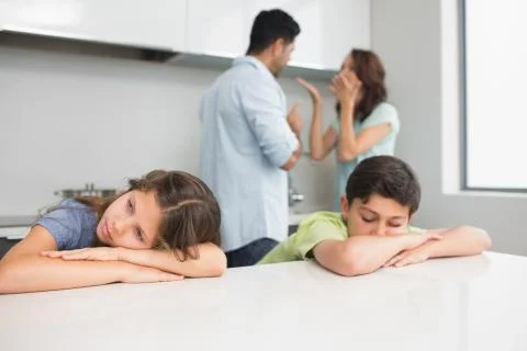 Sad young kids while parents quarreling in kitchen Stock Photos