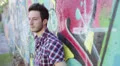 sad young man is crying because of his problems against a wall with murals HD Footage
