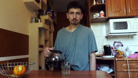 Sad young man pours coffee in the apartment Stock Footage 134646172