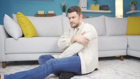 The sad young man sits alone in the living room and thinks about his experiences Stock Footage 233032164