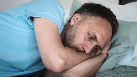Sad young man think lying down on bed alone. Tired middle-aged person in stress Stock Footage 249161773