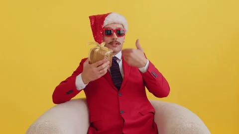 Sad young mustache man in a red suit and santa hat with red funny glasses Stock Footage 165555841