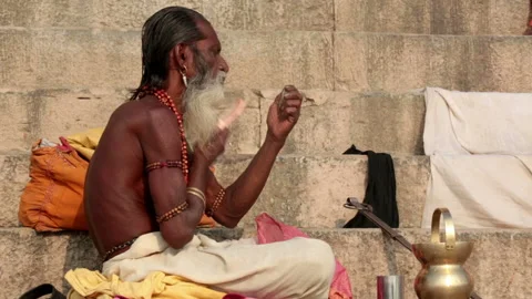 Sadhu combing his beard and mustaches on the stairs of the ghat Stock Footage 133039625