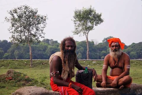 Sadhus sit wearing orange wraps, turban and religious marks on their arms. Stock Photos