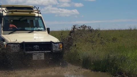 A safari machine drives through a mud pit making splashes Video stock 104995983