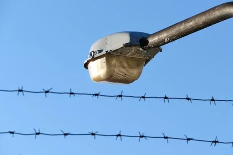 Safety and security at the facility. Barbed wire and spotlight. Stock Photos
