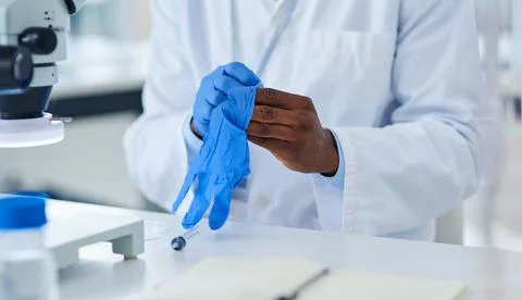 Safety first. Closeup of an unrecognizable scientist putting protective gloves Stock Photos