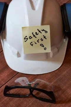 Safety first note one yellow piece of paper stuck on wooden background with f Stock Photos