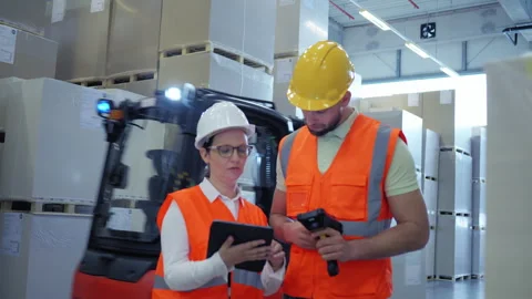 Safety gear workers inspect cargo in a warehouse. 库存影片 307998023