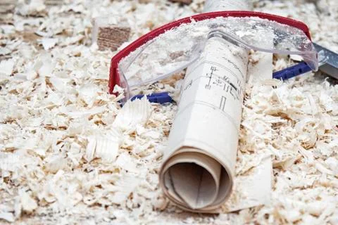 Safety glasses with a construction plan on the background of sawdust. Concept Stock Photos