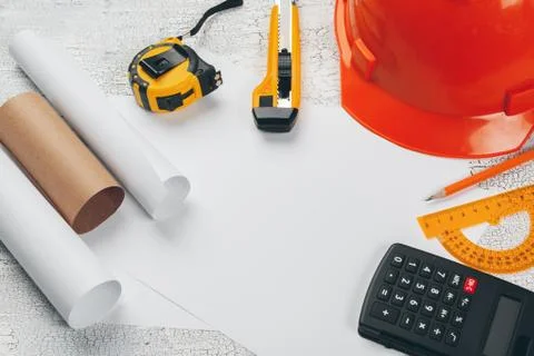 Safety helmet and Scrolls of engineering drawings and supplies Stock Photos